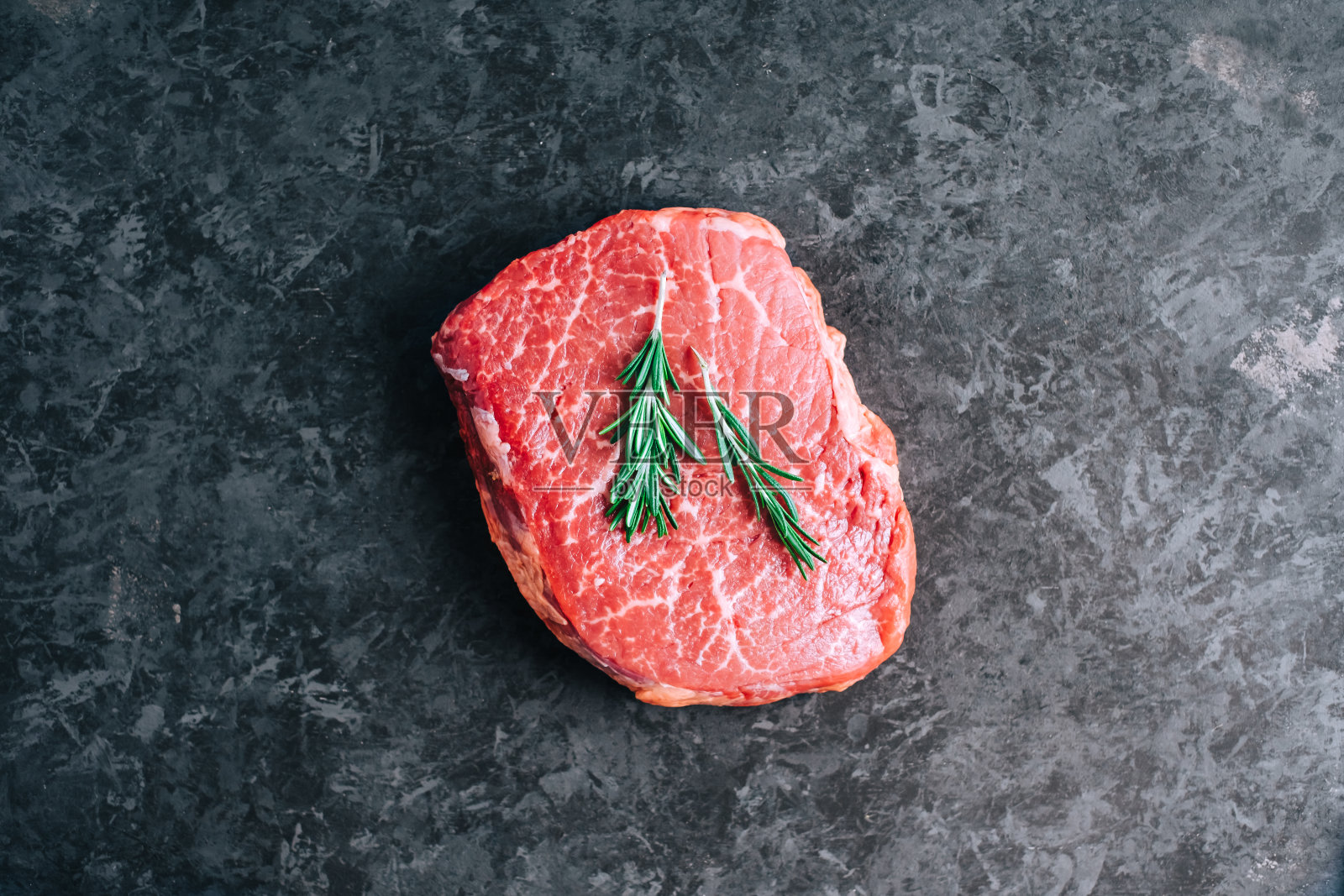 生牛排在黑色背景和迷迭香，俯视图。照片摄影图片