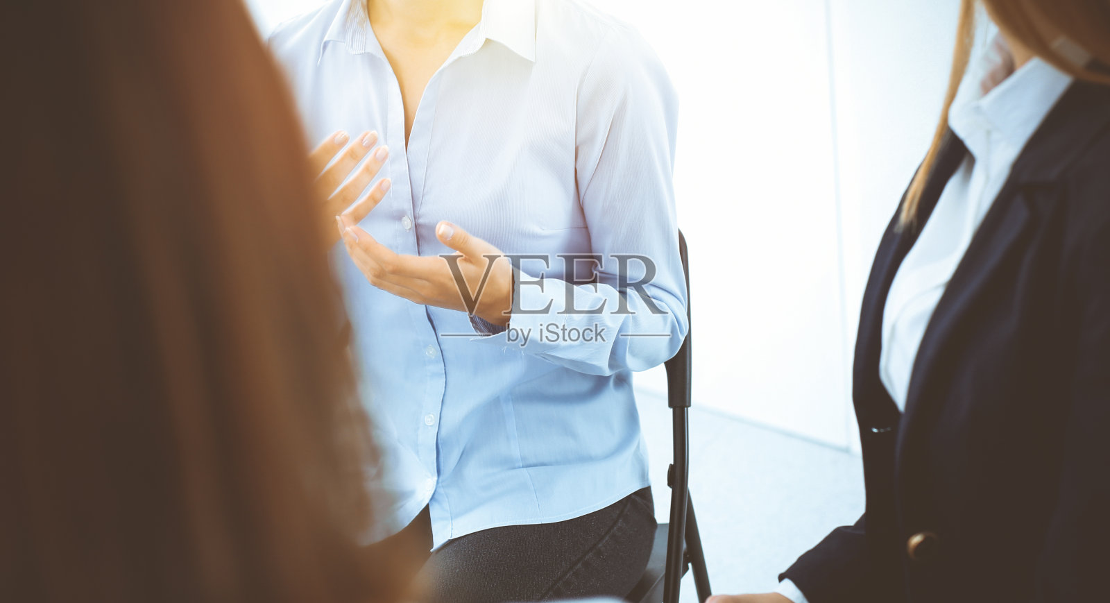 在阳光明媚的办公室里，一群人围坐成一圈。参加培训的业务团队的会议照片摄影图片