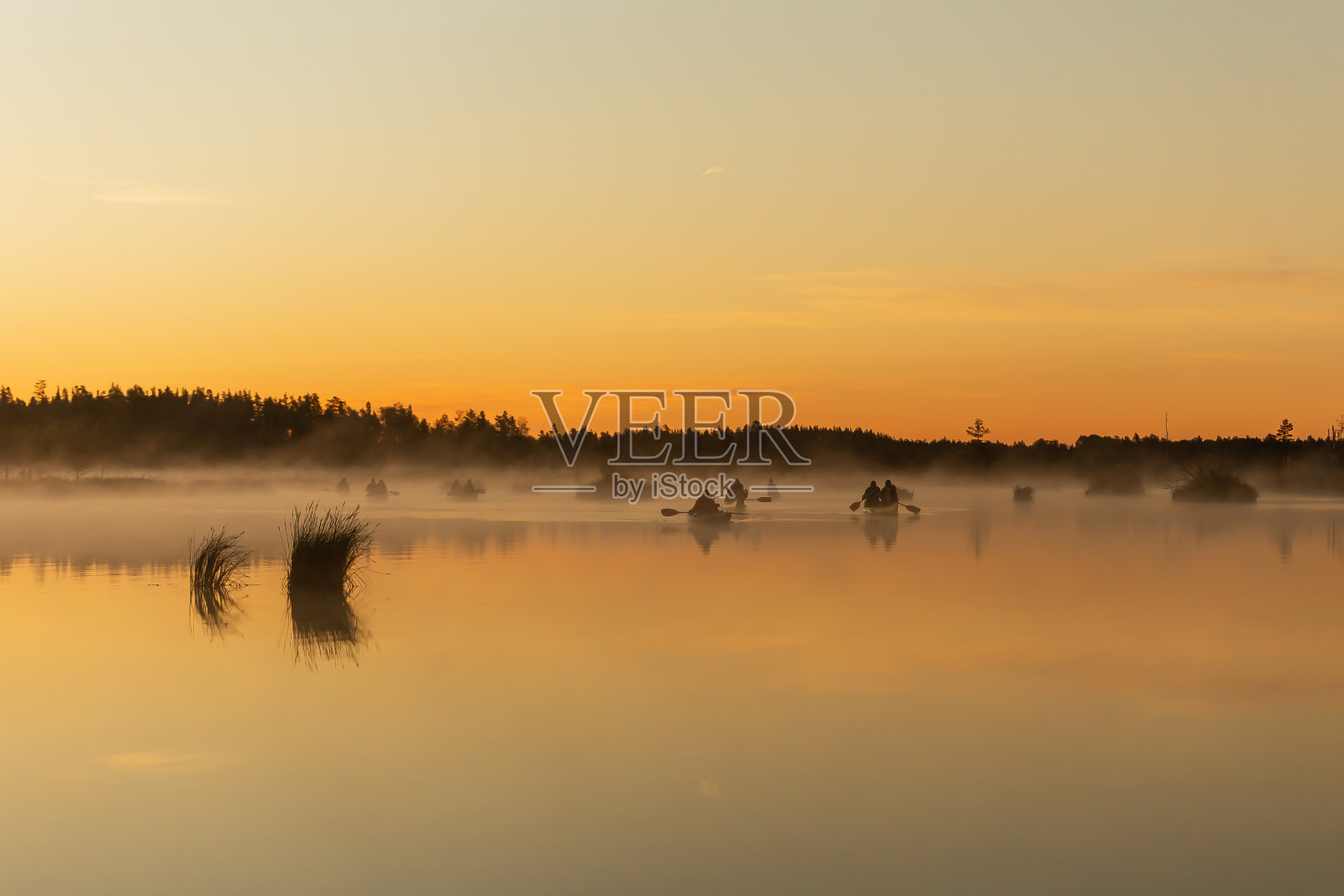 湖面上日出时独木舟的剪影。初夏的早晨照片摄影图片
