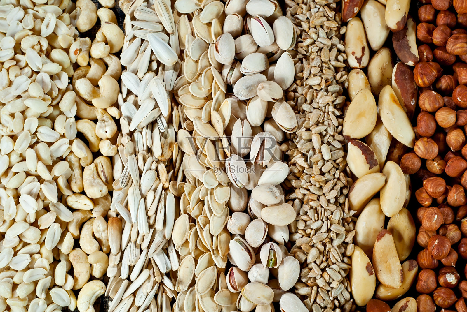 很多种类的坚果都是近距离的。一堆坚果放在一块黑木板上。坚果堆放在桌子上。照片摄影图片