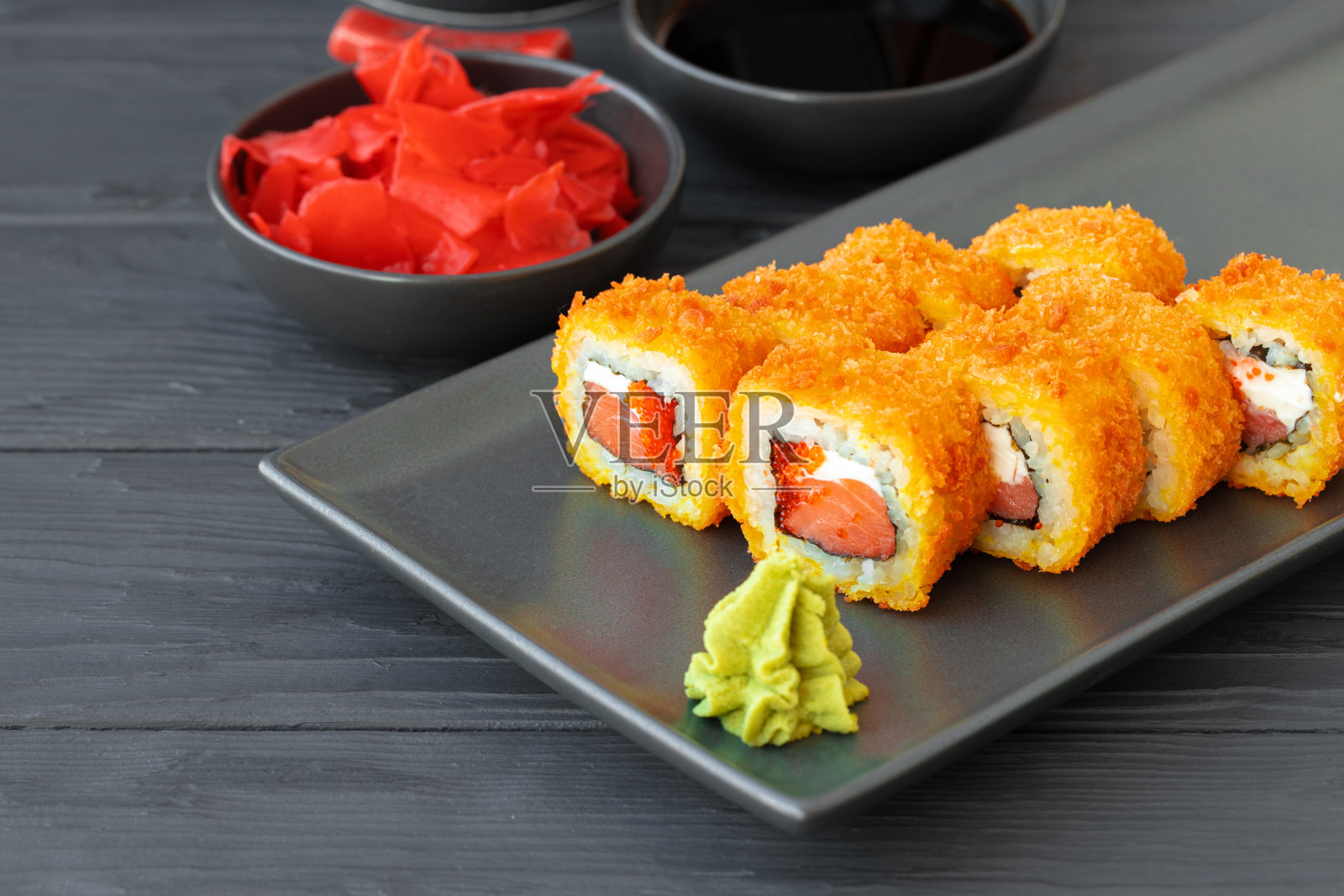 在黑色的盘子里用天妇罗炸寿司卷照片摄影图片