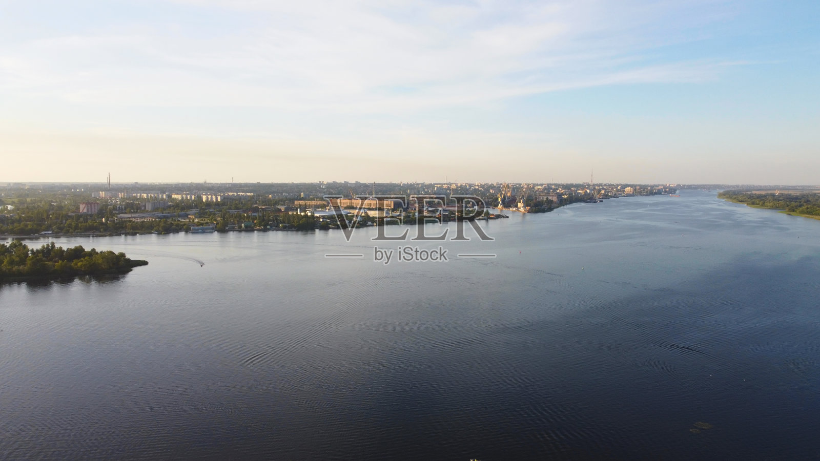 无人机飞过波浪起伏的河流，周围是当地的村庄，有各种各样的建筑和湿地和沼泽栖息地，芦苇床鸟瞰图。前视图。照片摄影图片