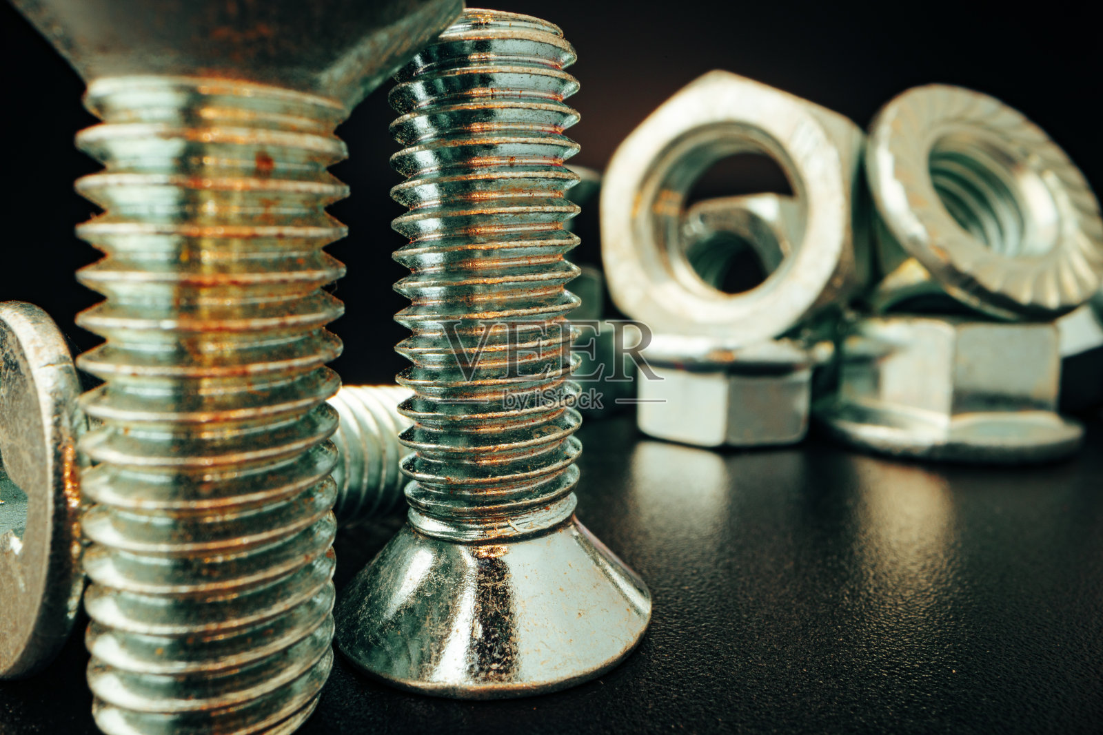 黑色背景上的金属螺丝和螺母照片摄影图片