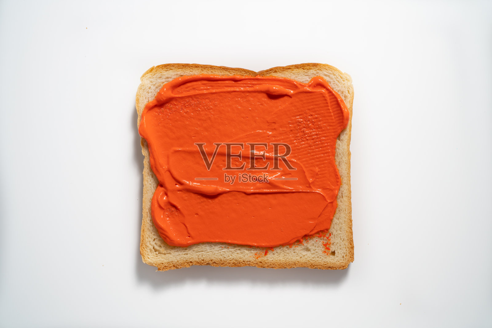 在白色背景的吐司上涂上橙色酱。俯视图照片摄影图片