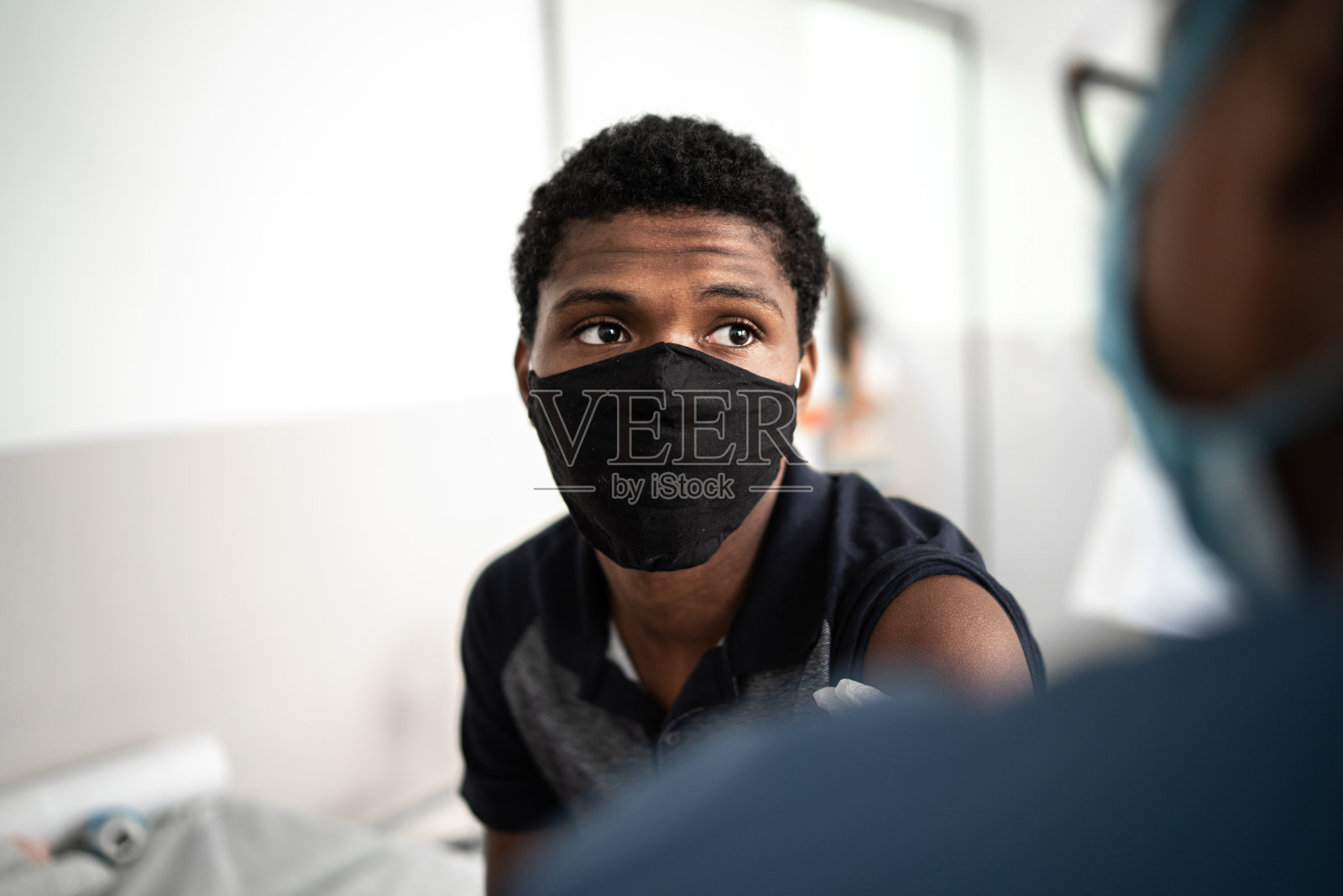 医生为青少年男孩接种疫苗 - 戴着口罩照片摄影图片