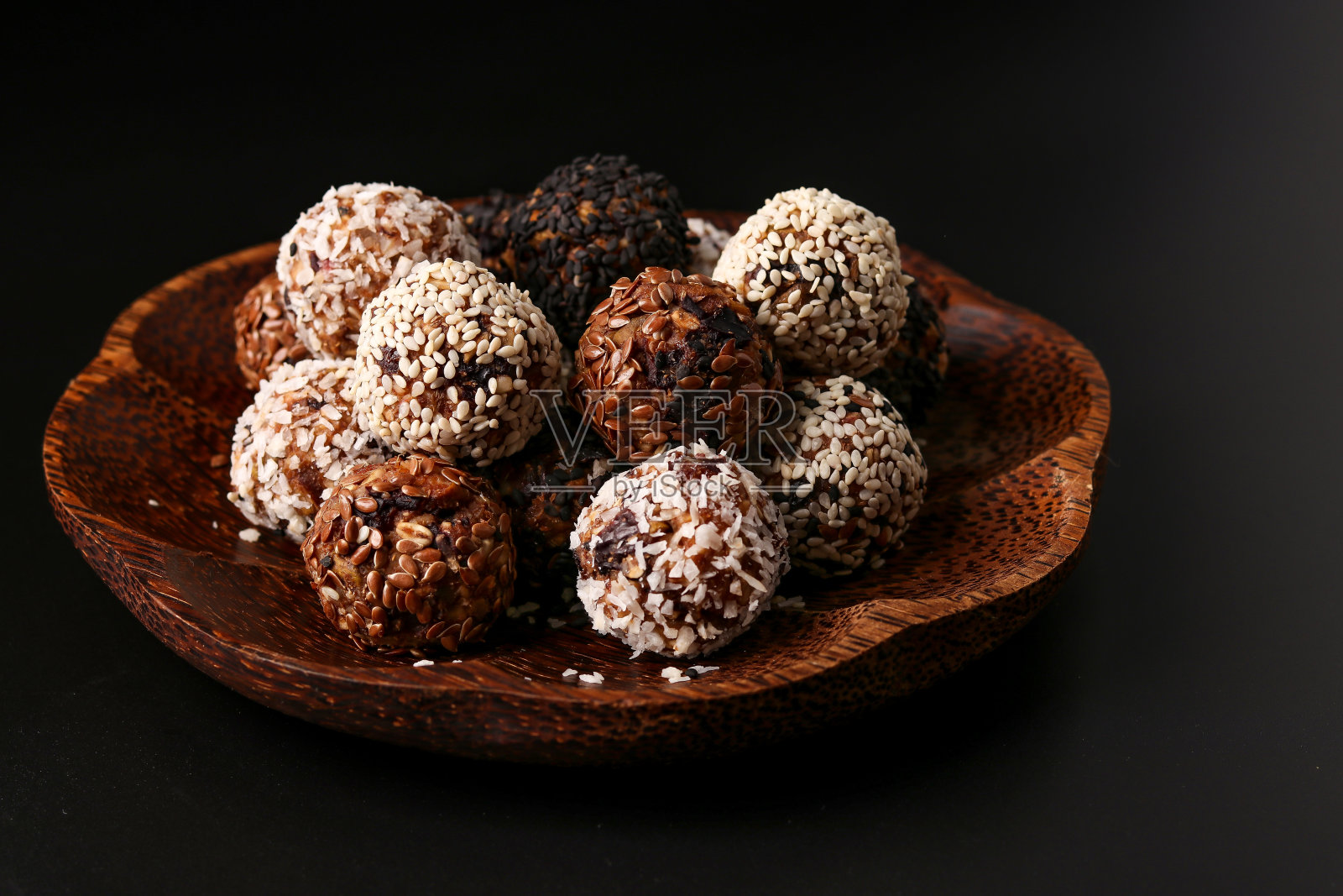 能量球坚果，燕麦和干果放在木椰子盘上，深色背景，水平方向照片摄影图片