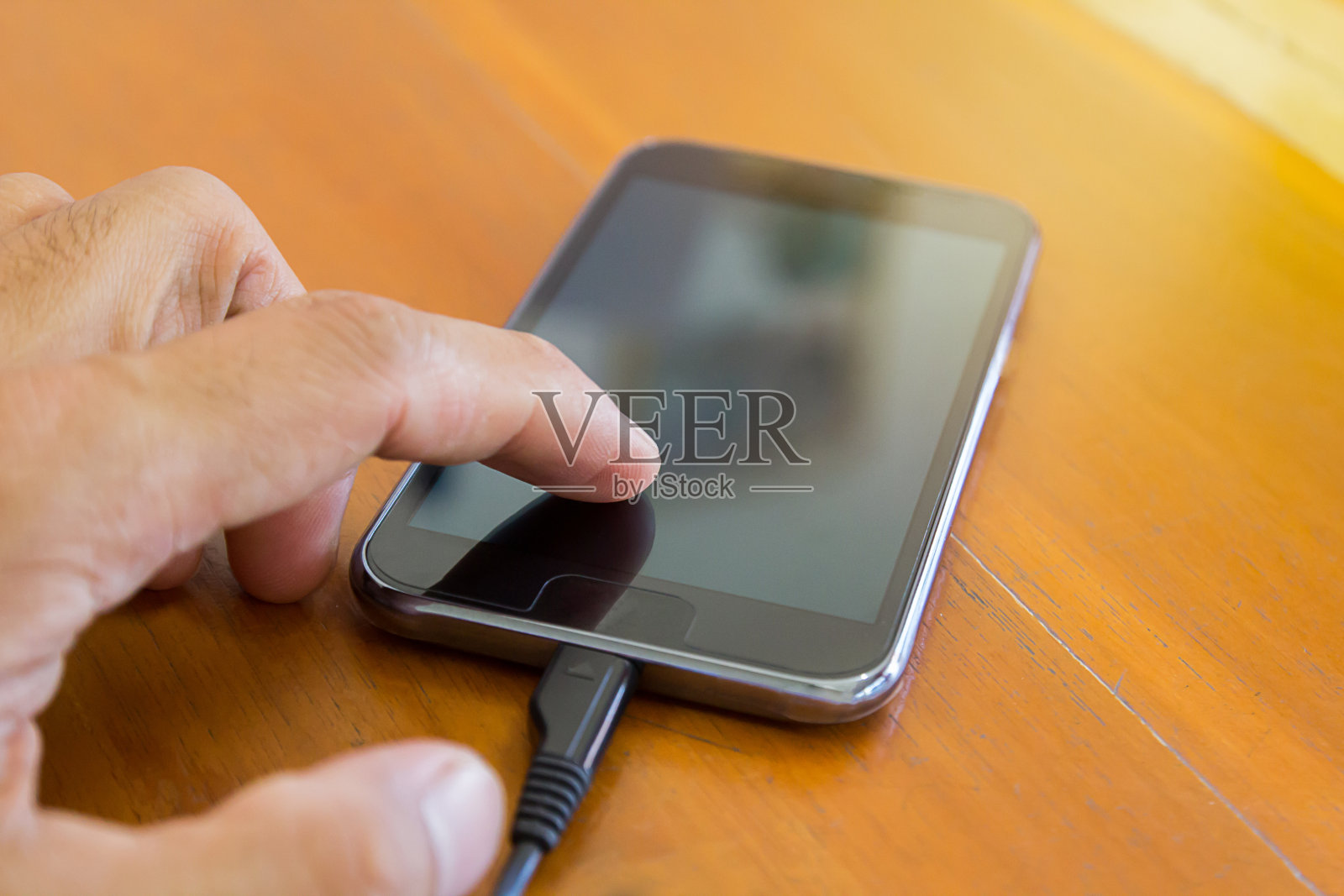 选择性对焦-手触摸和使用手机，手机，智能手机在木桌上照片摄影图片