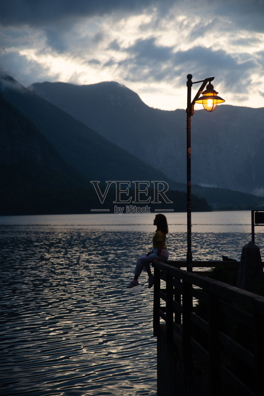 女人在老木码头看日落在哈尔斯塔特湖照片摄影图片