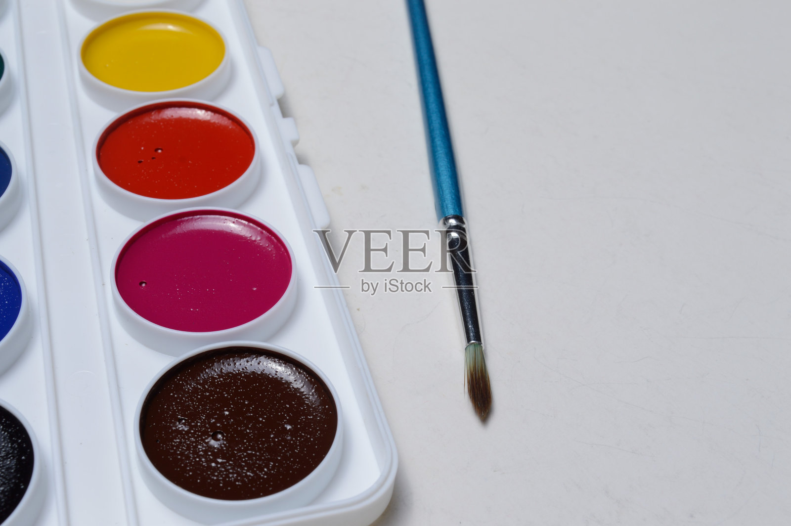 用调色板和画笔绘制的多种颜色的颜料。在一个明亮的背景特写。照片摄影图片