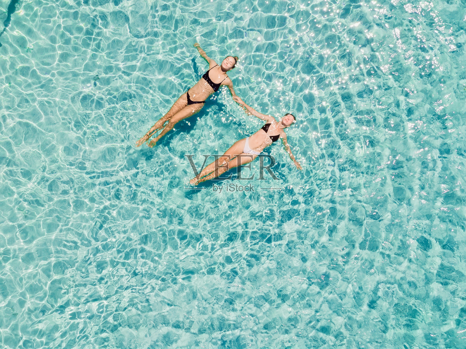 一对女人漂浮在湛蓝的大海上。鸟瞰图照片摄影图片