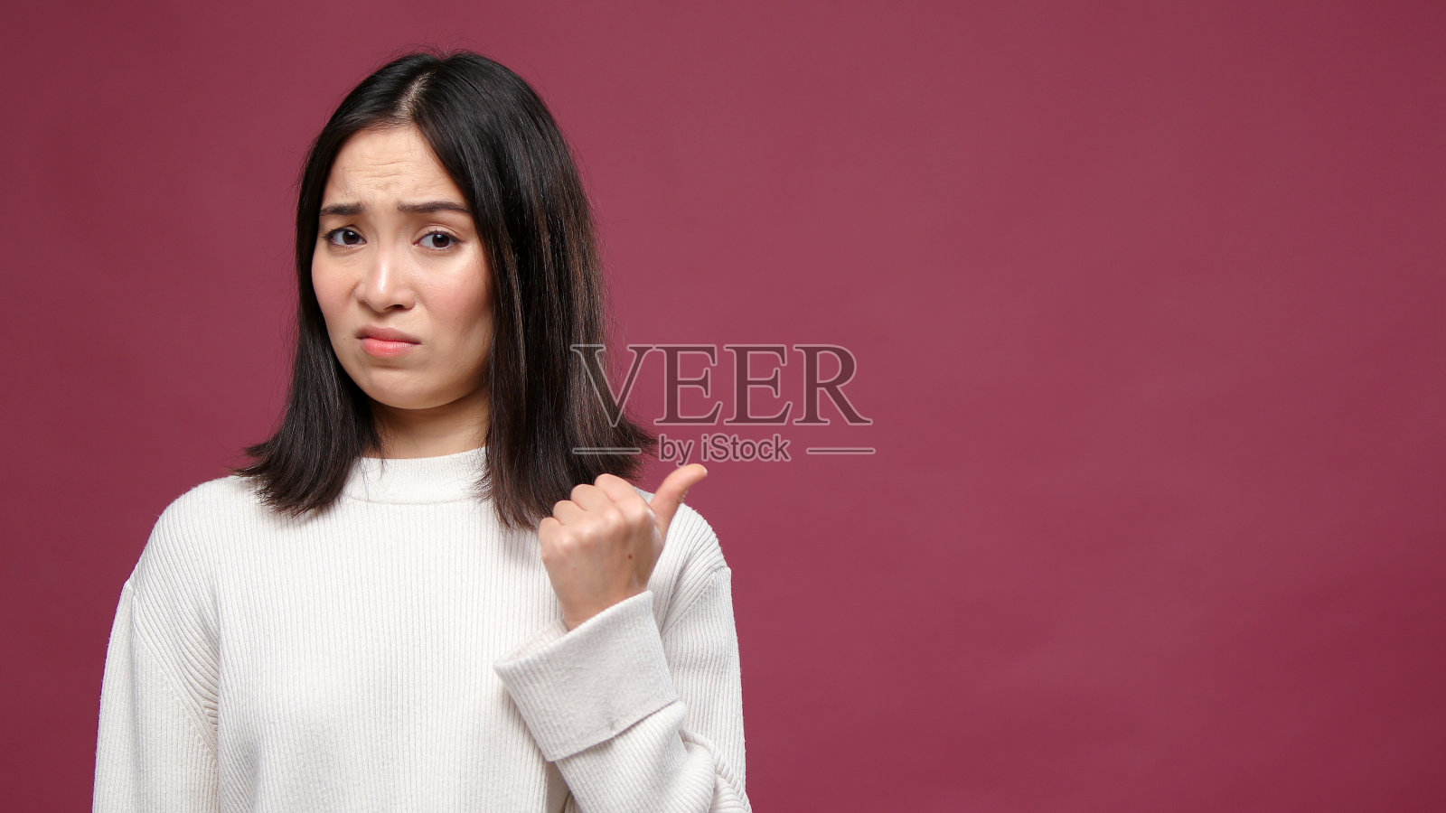 年轻的亚洲女子扬起眉毛，指着马萨拉copyspace大拇指照片摄影图片