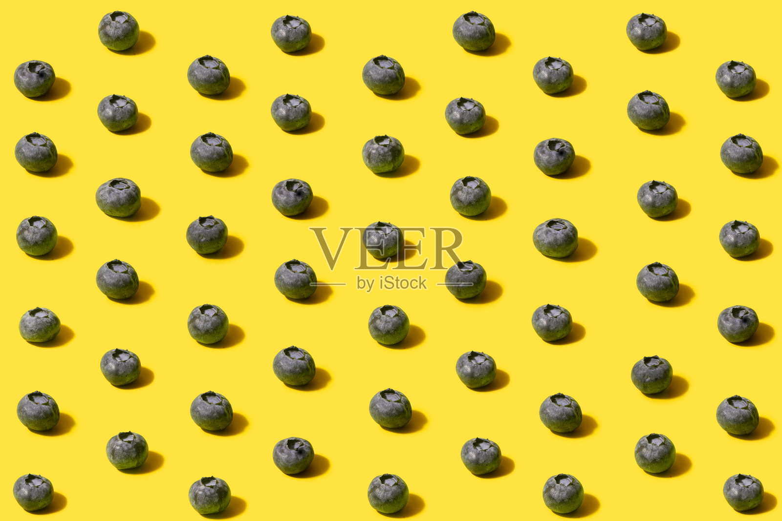 有机天然新鲜水果的最小模式-蓝莓。安排与超现实的黄色背景。照片摄影图片