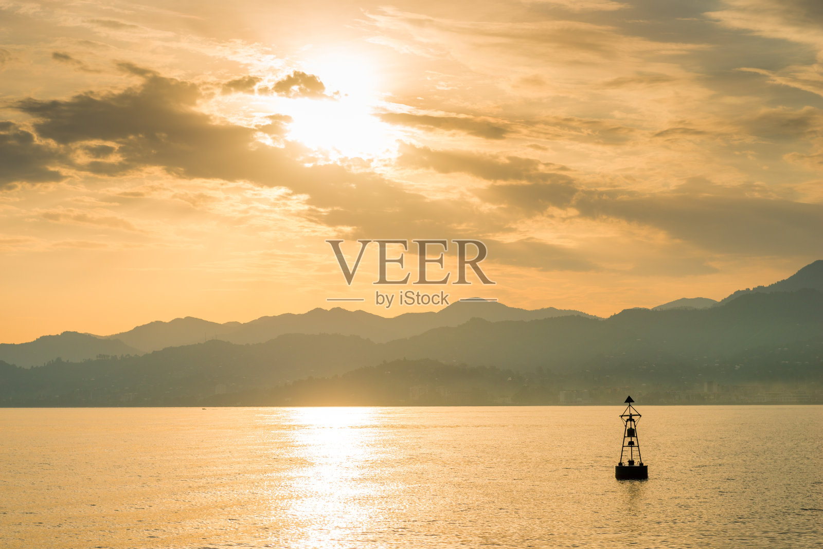 海上孤独的灯塔浮标，映衬着风景如画的群山照片摄影图片