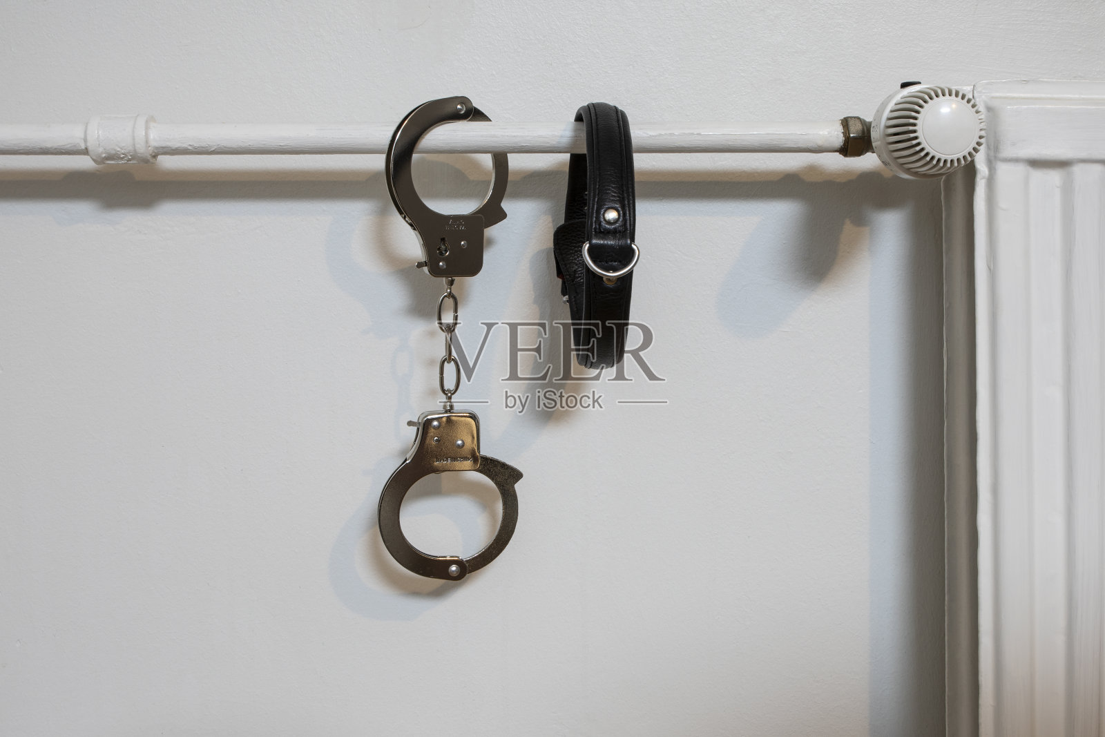 散热器上有手铐。警察的手铐和衣领。照片摄影图片