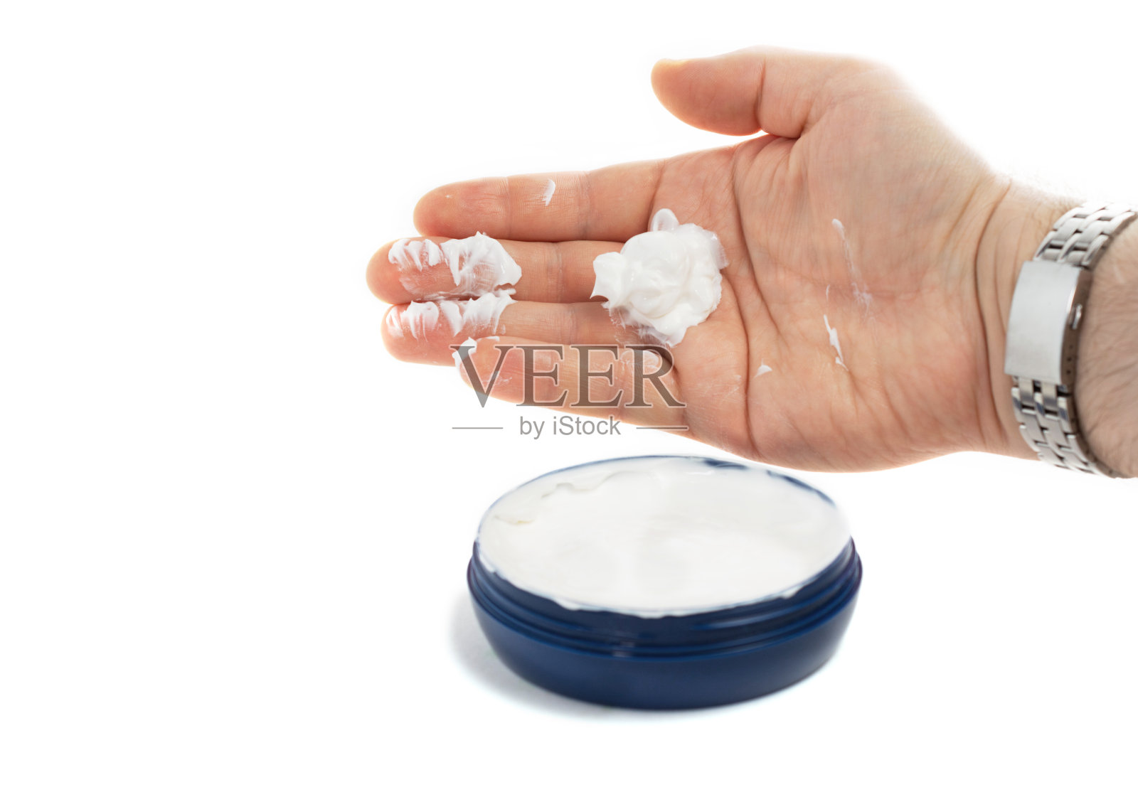 那人用手掌从一个蓝色的罐子里拿了一瓶白色的护手霜。美容理念，干性肌肤，保湿肌肤。白色背景。照片摄影图片