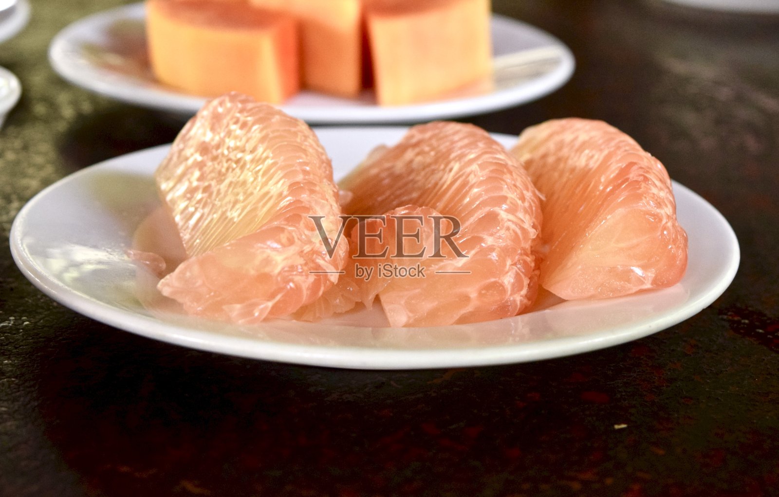 白盘子里的葡萄柚。照片摄影图片