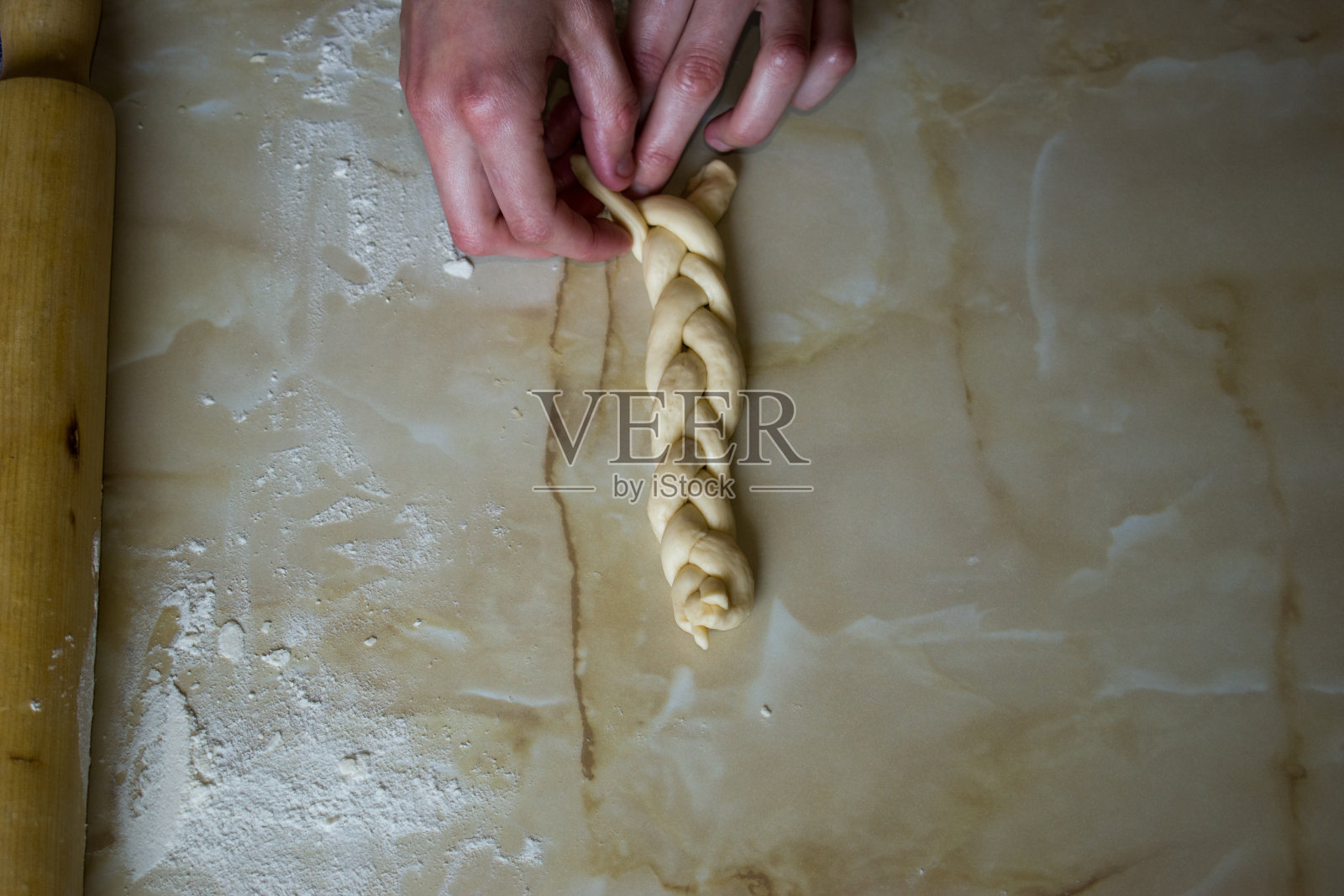 女人，女人的手在厨房桌上编织面团。俯视图照片摄影图片