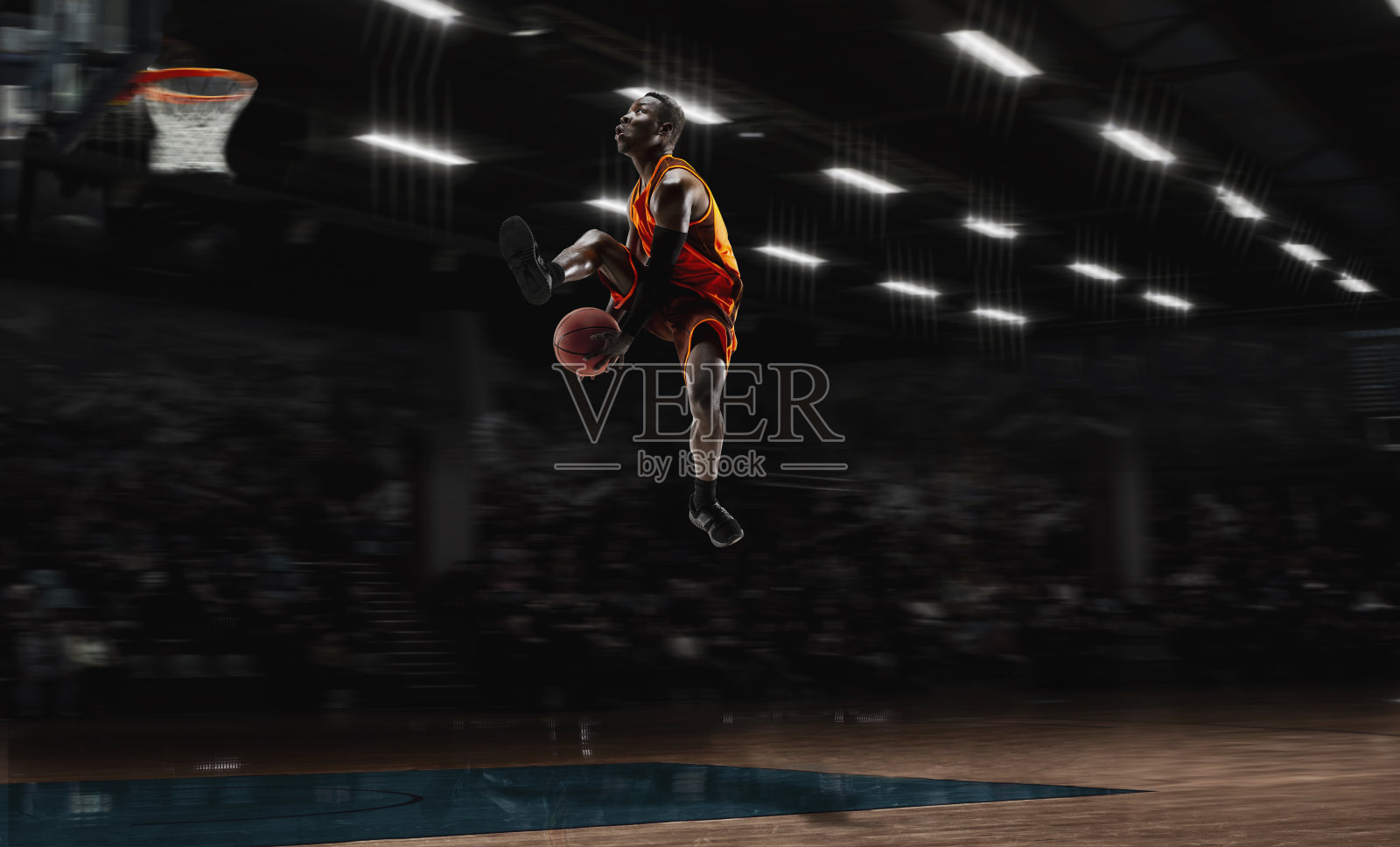 非裔美国青年篮球运动员在行动和手电筒在体育馆的背景。运动的概念，运动，能量和动态，健康的生活方式。照片摄影图片