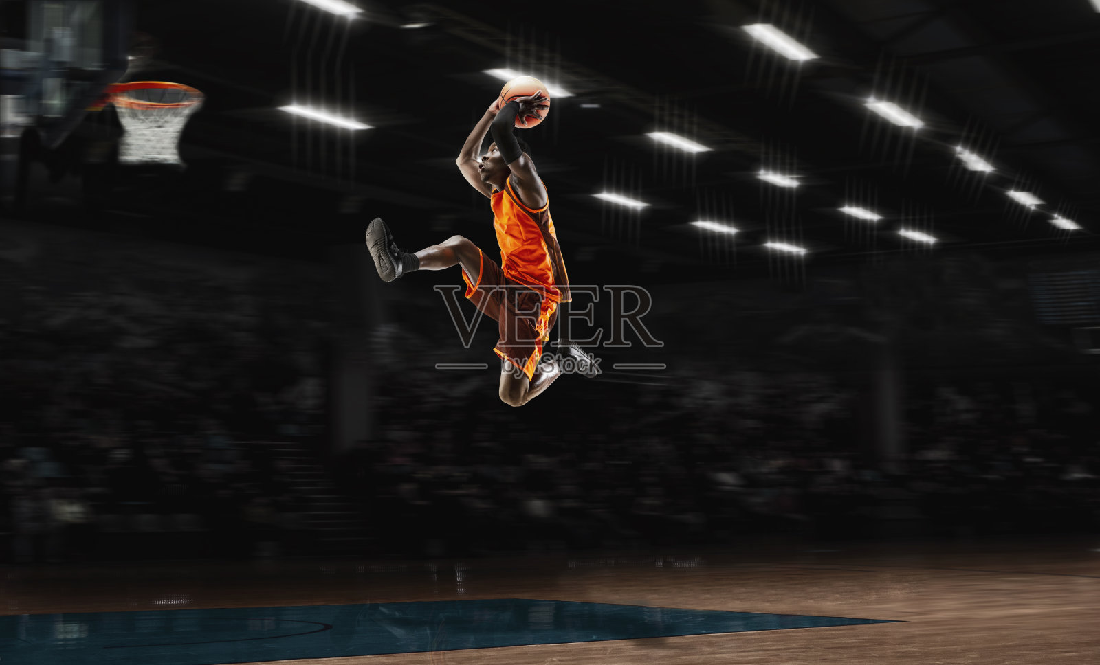 非裔美国青年篮球运动员在行动和手电筒在体育馆的背景。运动的概念，运动，能量和动态，健康的生活方式。照片摄影图片