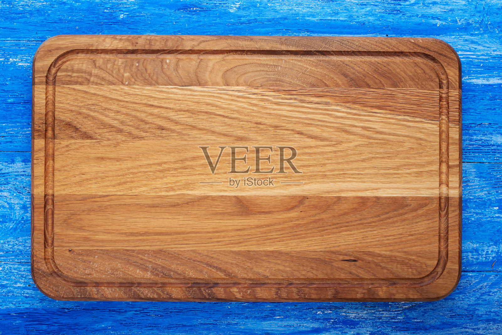 在蓝色的木桌上放一块长方形的砧板。空间的文本。照片摄影图片