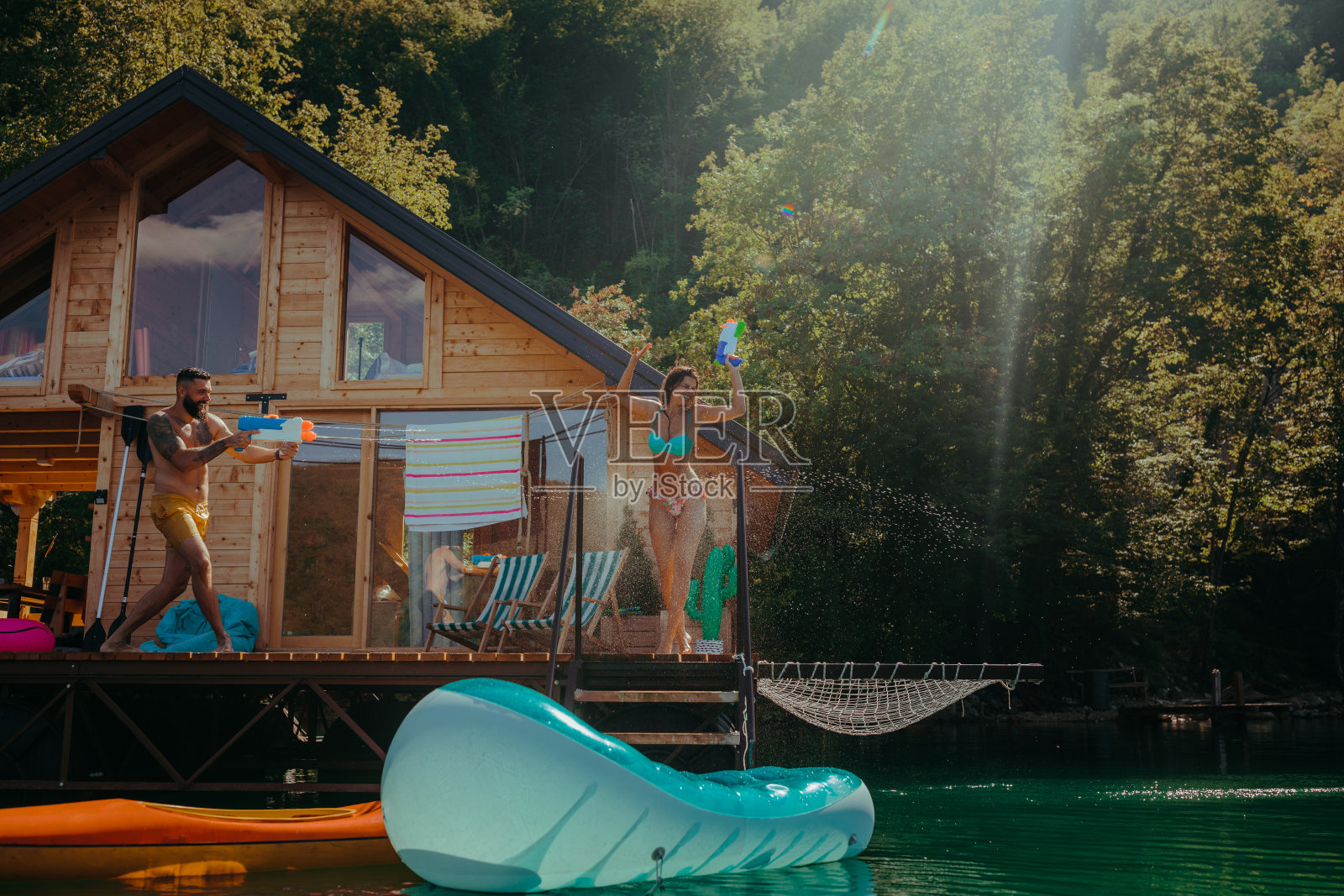 年轻夫妇在一个炎热的夏天玩水枪。照片摄影图片
