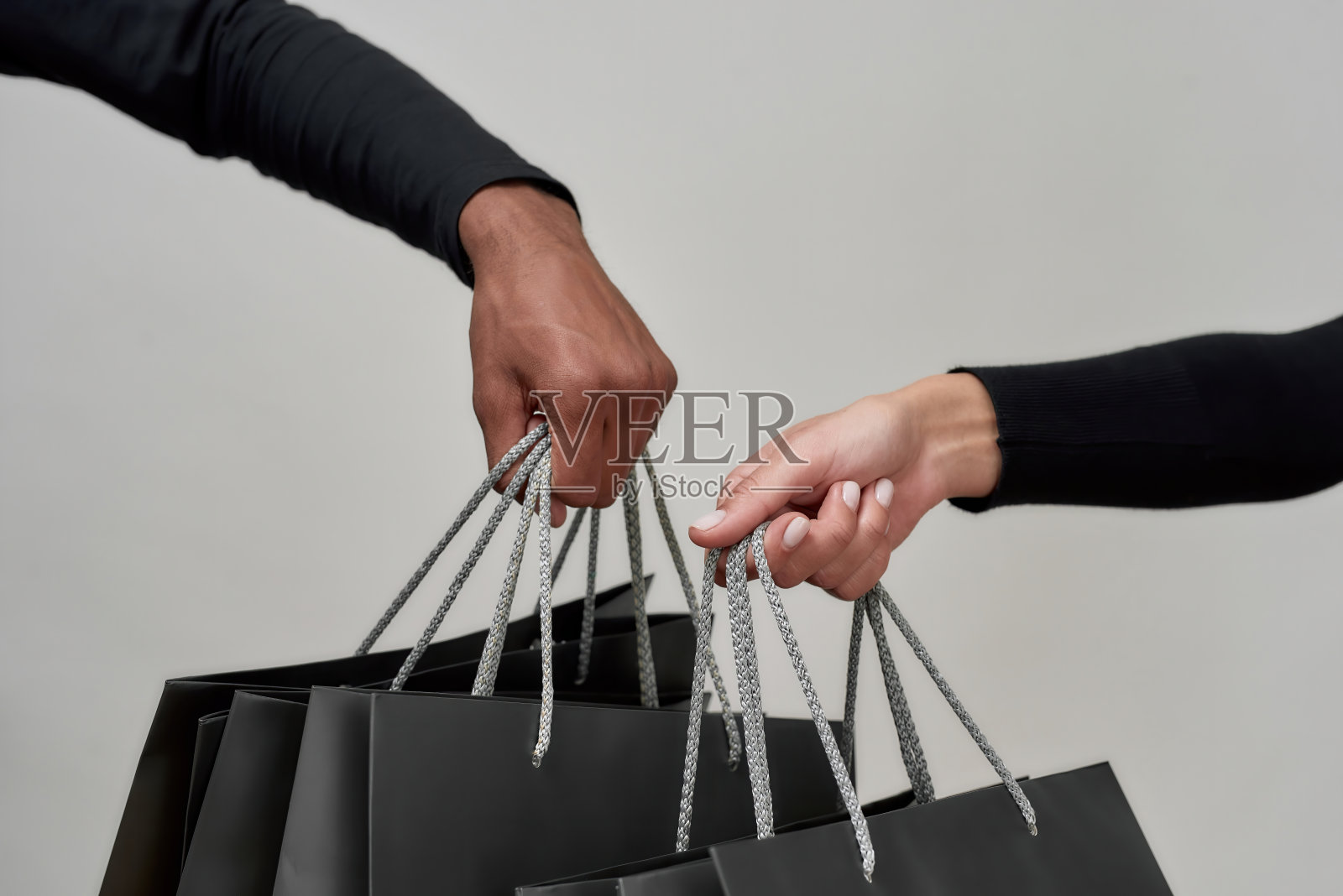 近距离拍摄，男女在一起购物后，手拿黑色纸袋孤立在灯光背景下照片摄影图片