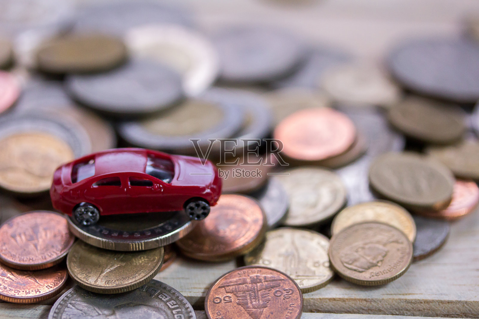 玩具车和硬币堆在木桌的背景上照片摄影图片