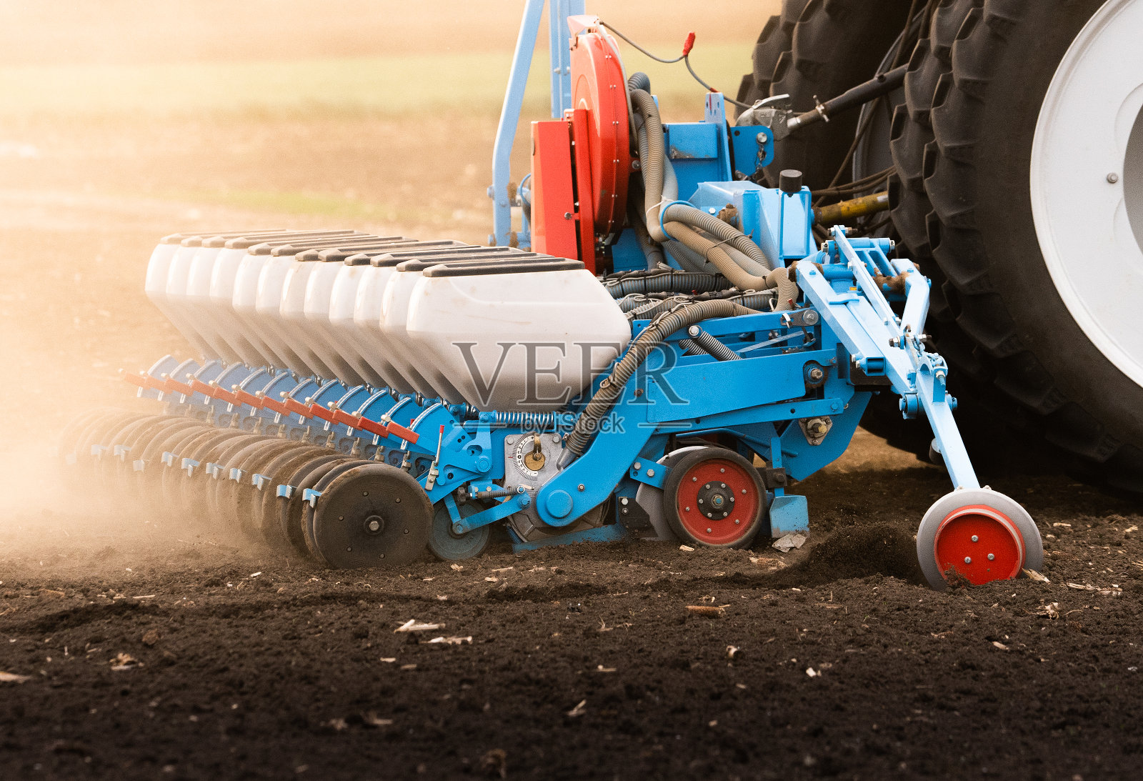 农民用拖拉机播种，在农田里播种庄稼。植物、小麦。照片摄影图片