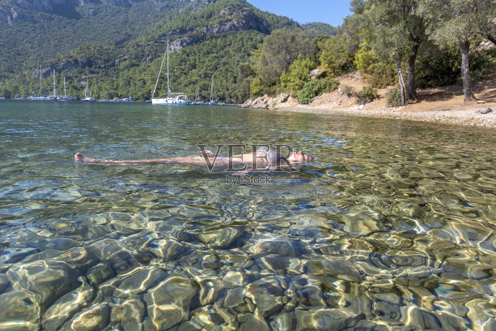 漂在大海里的女人。女人在阳光明媚的日子里游泳。照片摄影图片