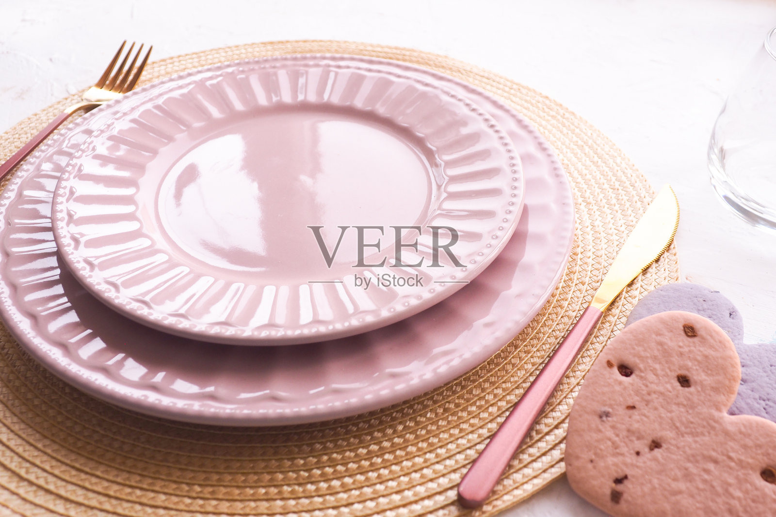 餐桌布置：白色桌子上的粉色空盘、勺子和叉子照片摄影图片