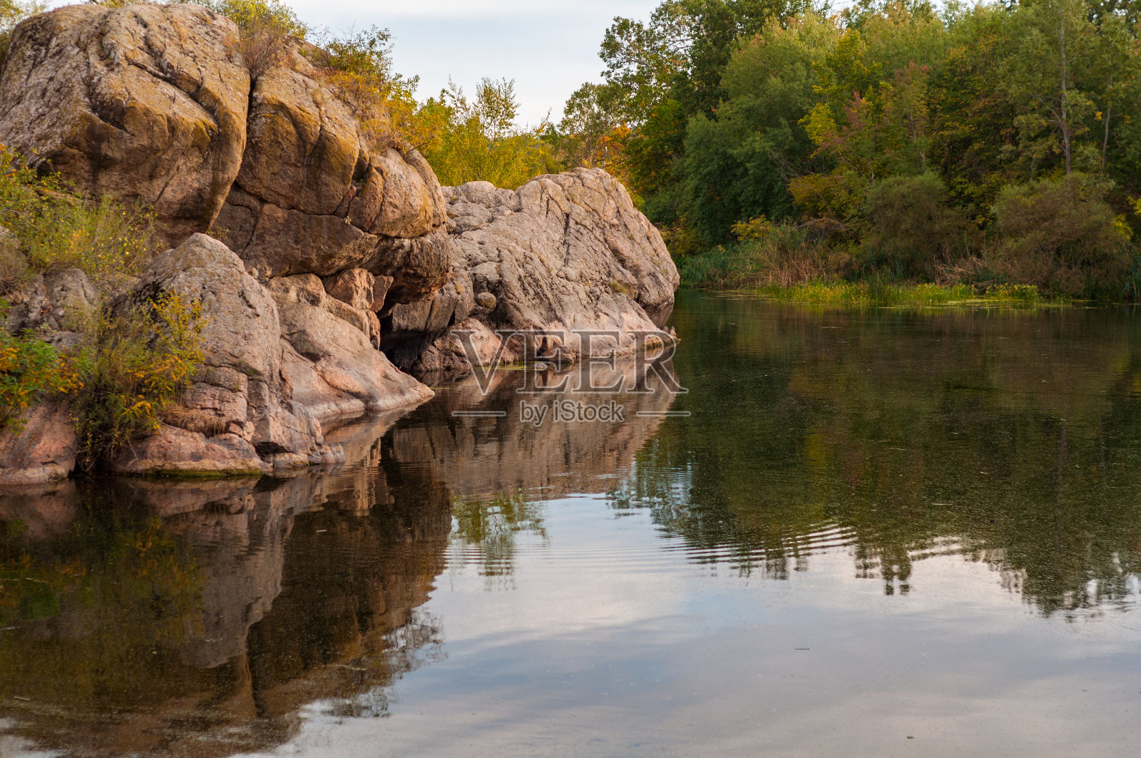 河岸风光秀丽，秋高气扬，山腰杂草丛生，花岗石雕垂至水面照片摄影图片