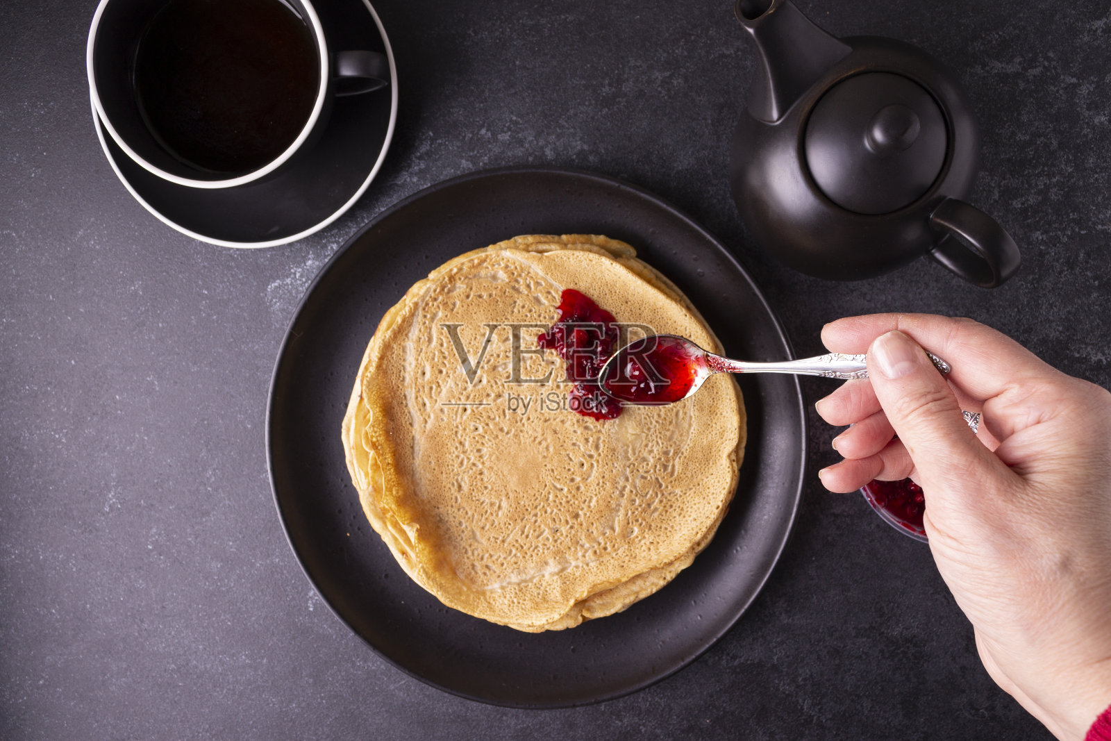 燕麦煎饼配越橘酱，黑色盘子，黑色背景。照片摄影图片