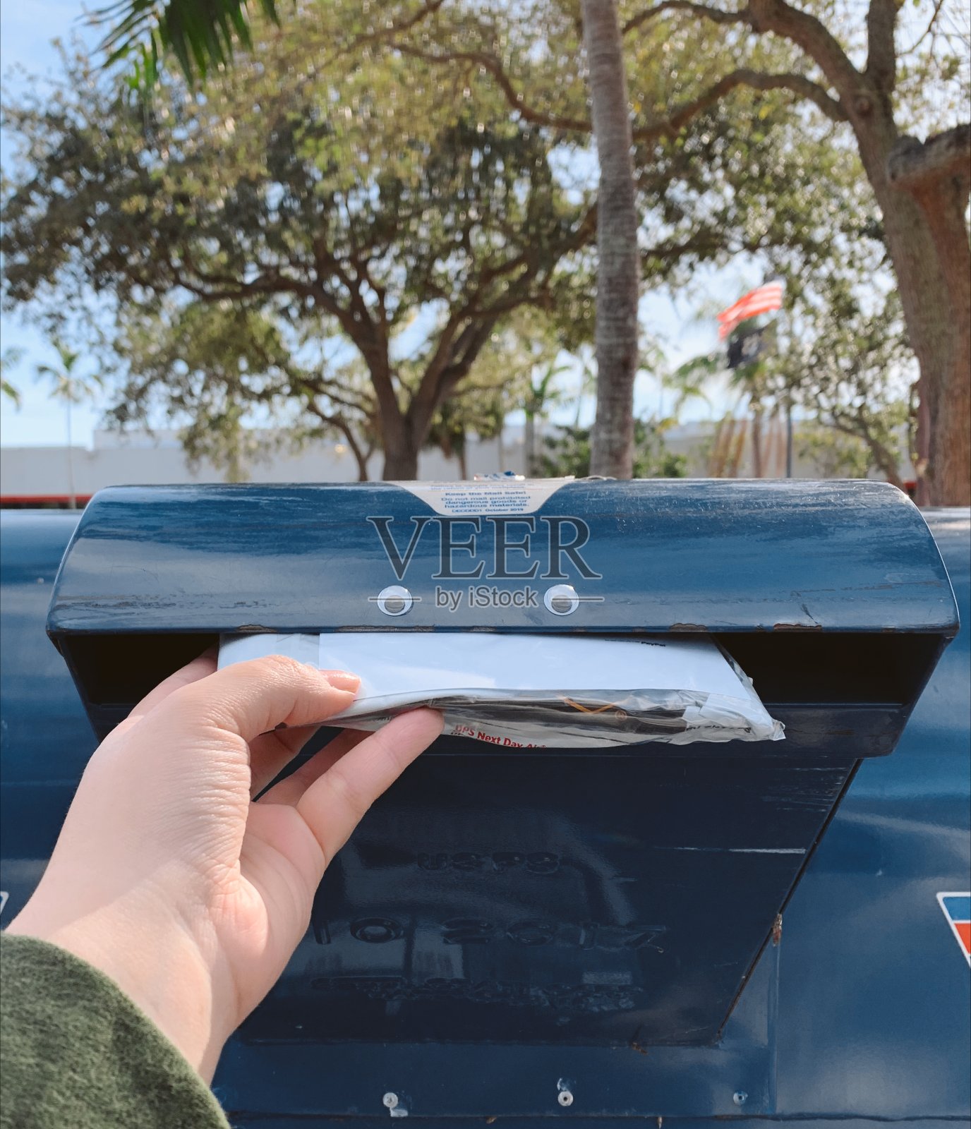 在佛罗里达州棕榈滩的邮局里，把一个包裹放在蓝色的长着眼睛的邮箱里照片摄影图片