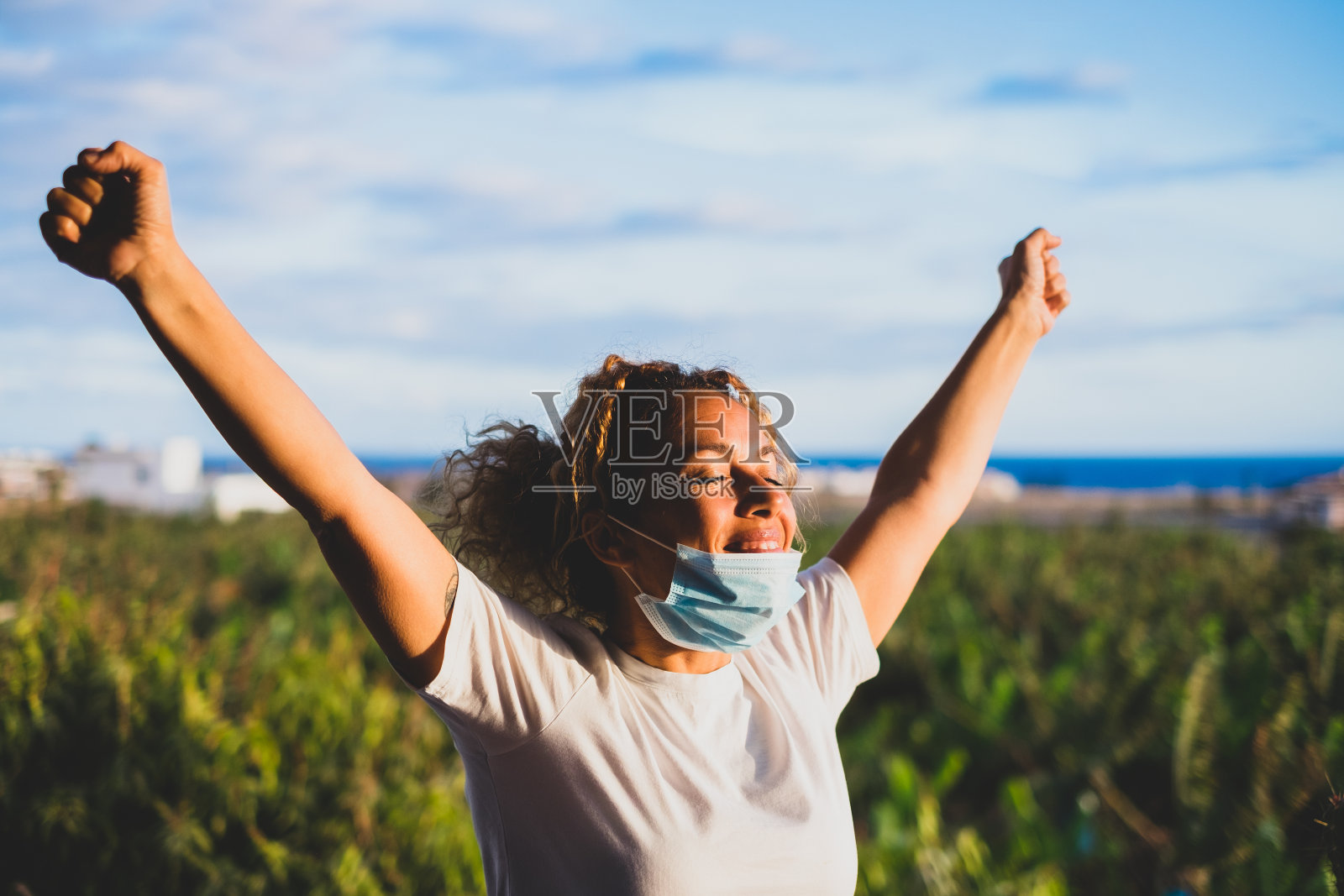 疫情隔离结束后在阳台上张开双臂的快乐卷发女人照片摄影图片