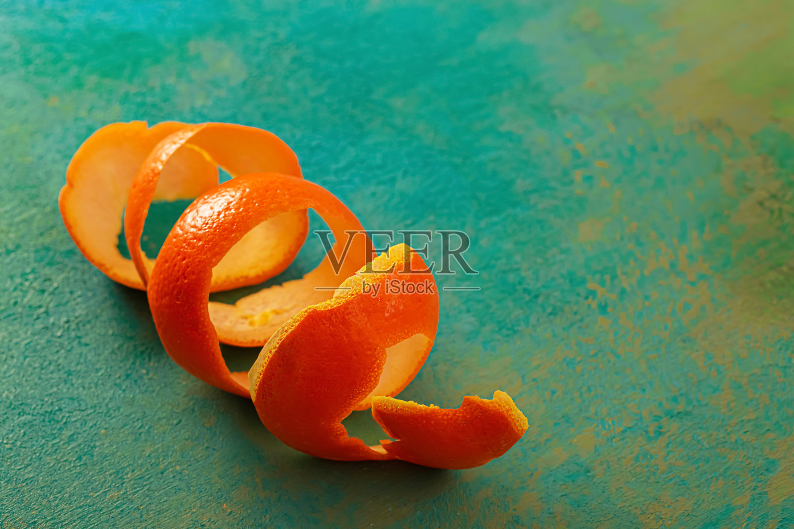 宏观螺旋柑橘类水果。背景与螺旋橘子皮在绿色木桌上。水果的艺术形象。纹理照片摄影图片