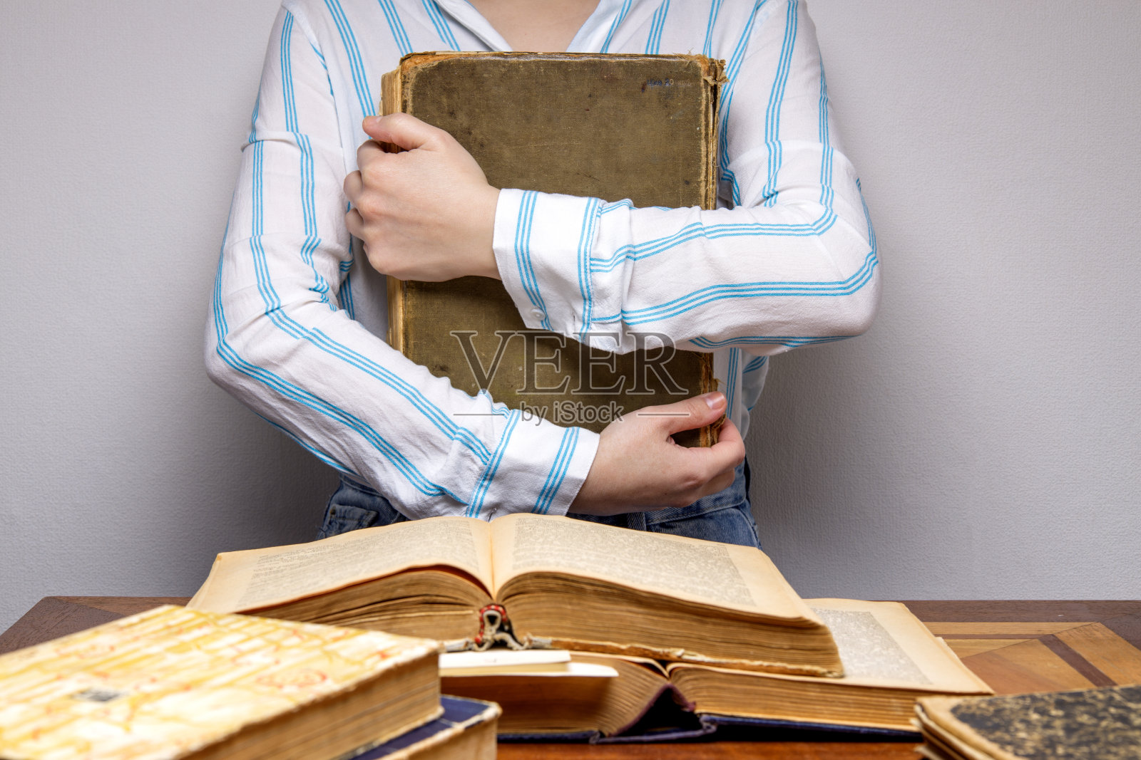 一个隐形人的手抱着一本旧书。照片摄影图片