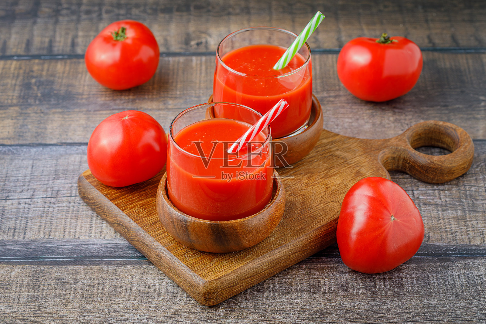 番茄汁装在玻璃杯里，吸管放在木板上照片摄影图片
