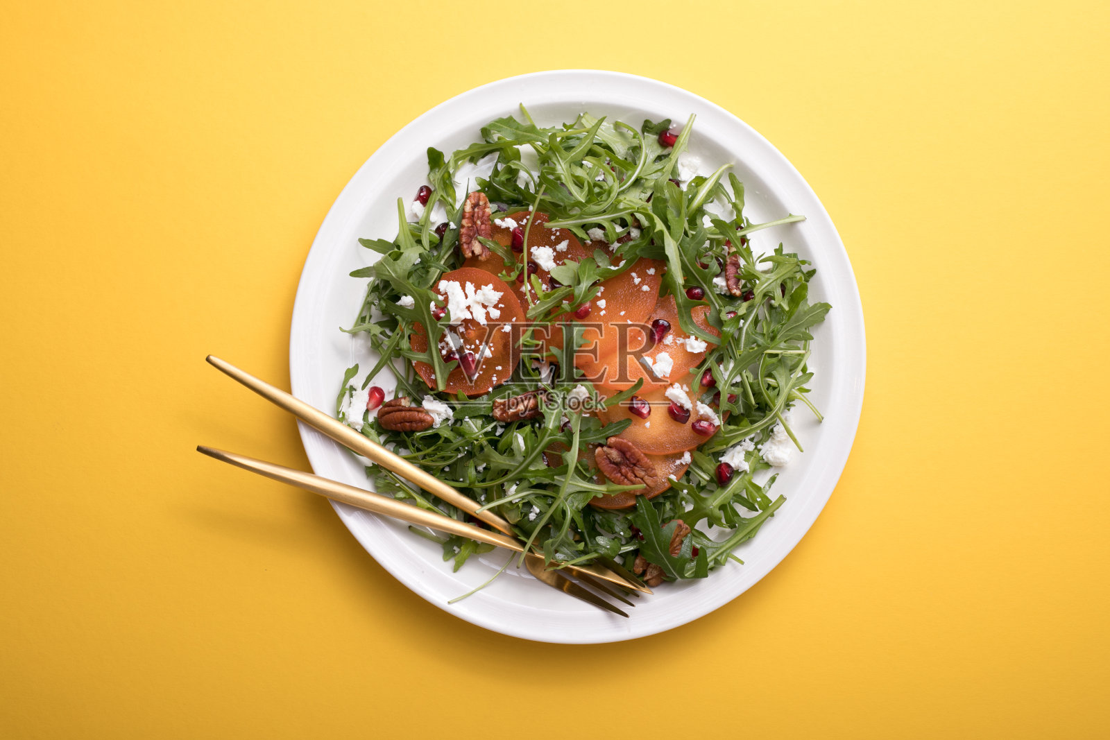 柿子沙拉配芝麻菜，坚果，山羊奶酪，石榴。健康素食沙拉概念。照片摄影图片