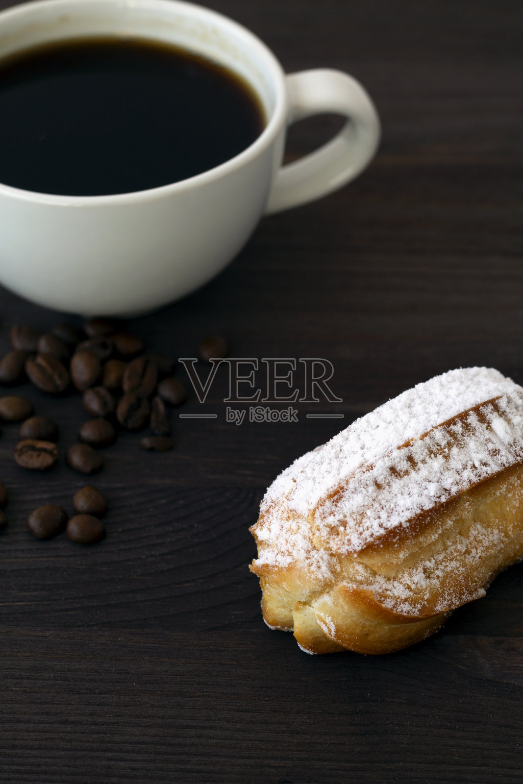 传统的法国美味甜点在黑暗的背景。木桌上放自制的香草泡芙条或小圆饼。副本的空间。一杯加豆子的黑咖啡。垂直照片摄影图片