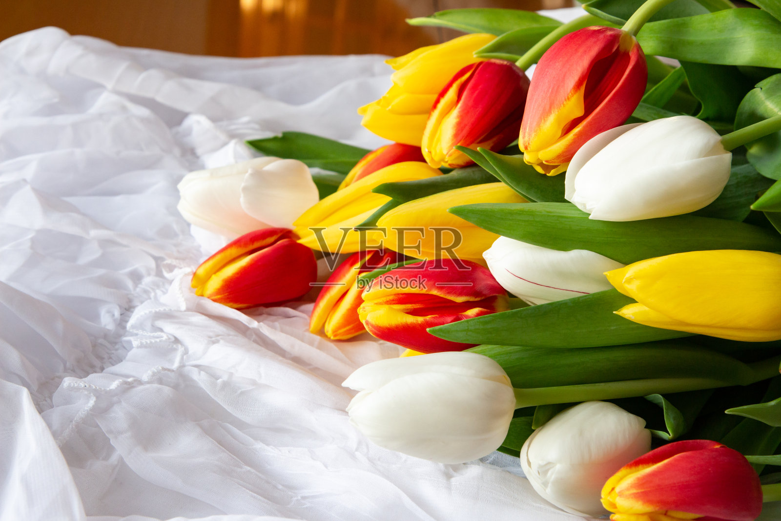 白色，黄色和红色的郁金香花束与水滴-白色的背景照片摄影图片