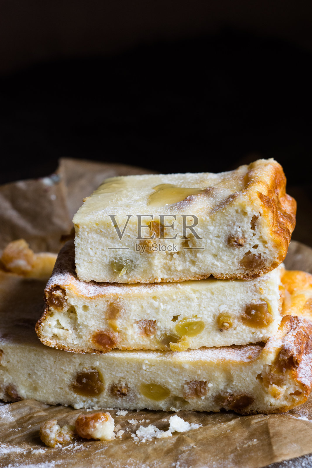 特写:在一张木桌上的烤纸上，放着农家干酪砂锅，上面放着葡萄干和蜂蜜。俄罗斯传统甜品zapekanka照片摄影图片