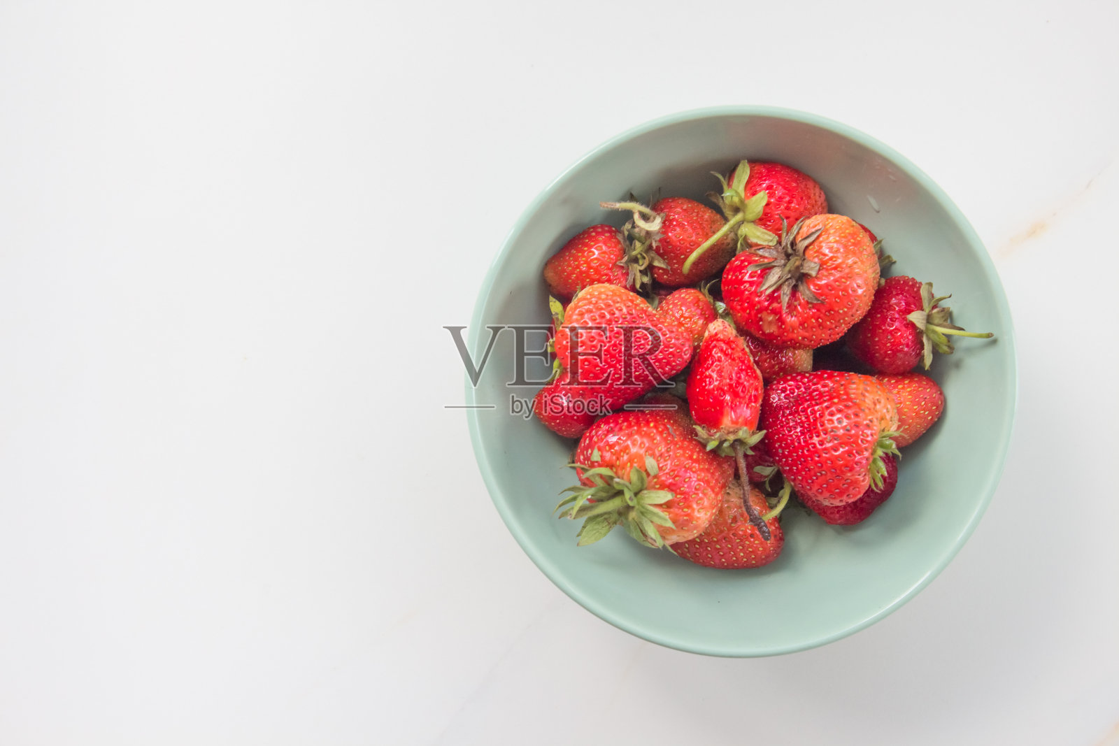 早期用杀虫剂种植的草莓。又硬又不甜的草莓，长得不对。碗里的草莓有文字空格照片摄影图片