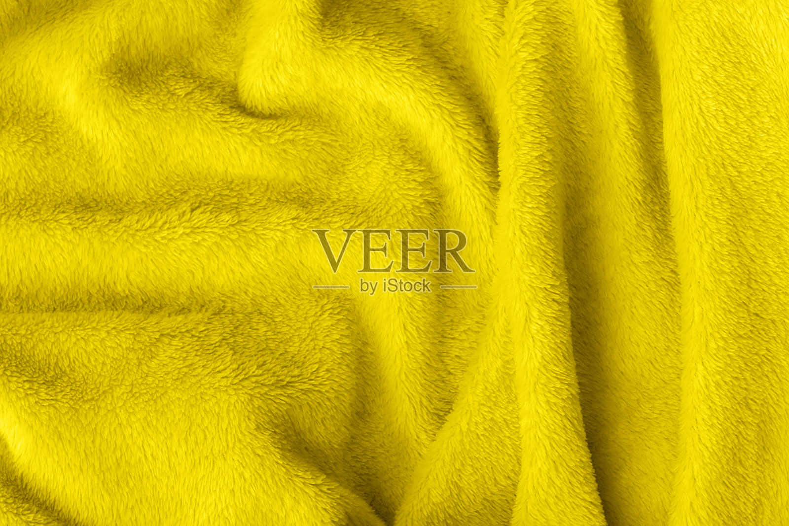 黄色透光绒毛织物质地。皱巴巴的纺织人造毛皮毯子背景。2021年色彩趋势照片摄影图片