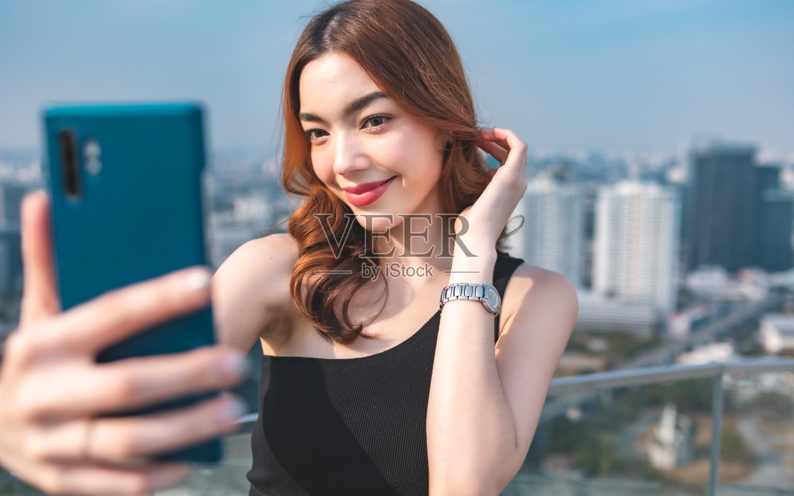 微笑的漂亮的年轻商业女性的肖像使用电话在办公室背景。穿着时尚的办公室服装，站在户外打电话。照片摄影图片