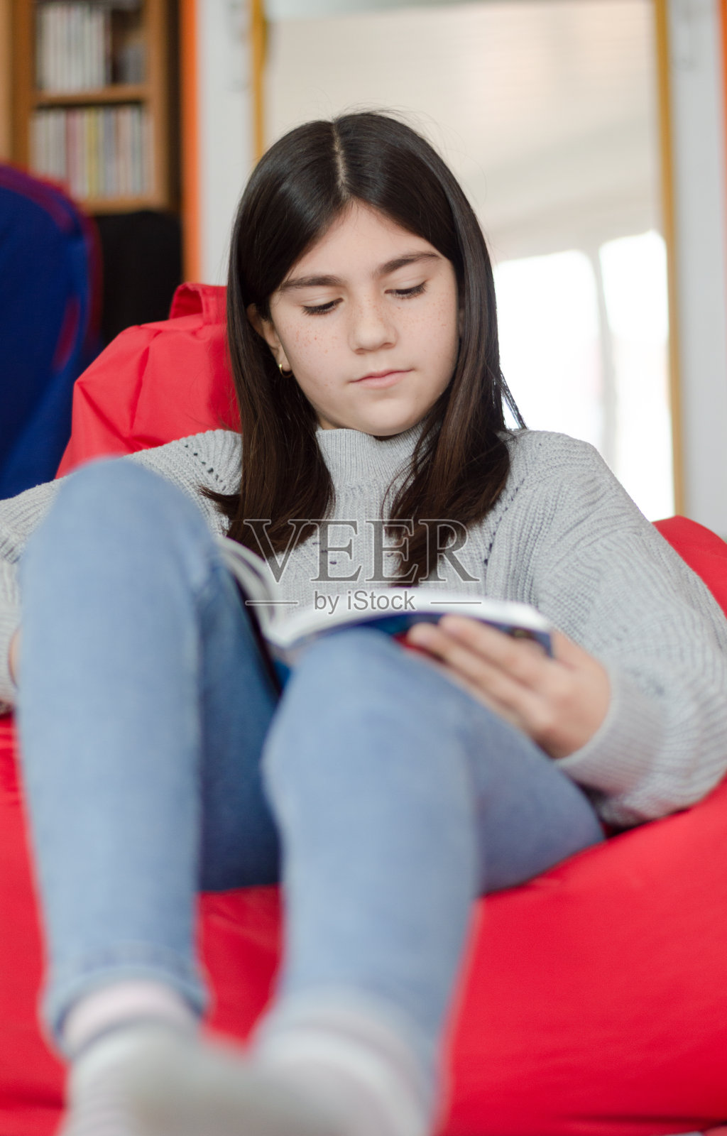 漂亮的小女孩在她的房间里看书照片摄影图片