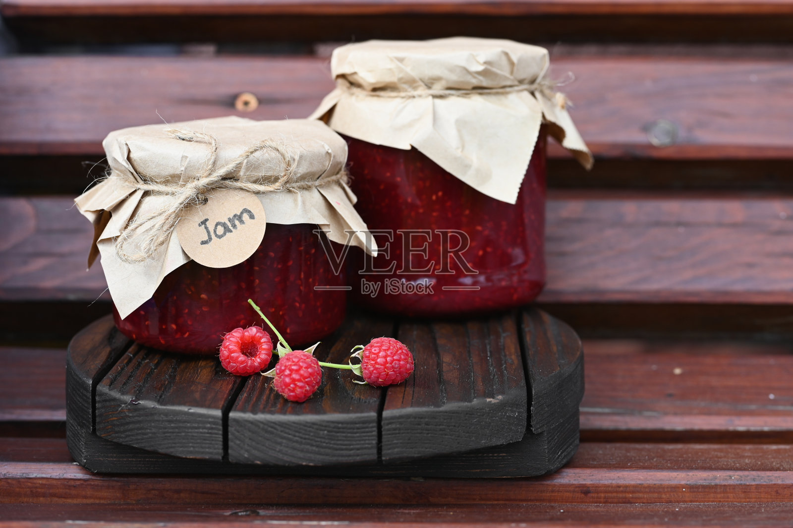 木制背景上自制的覆盆子果酱。照片摄影图片