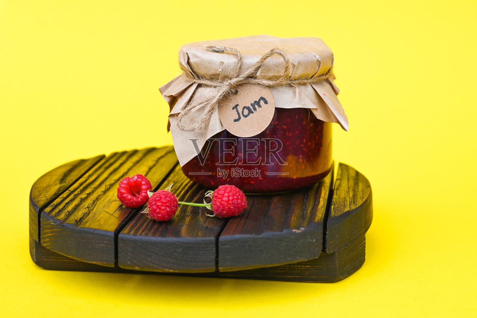 玻璃罐中的覆盆子果酱和黄色背景上的新鲜覆盆子。照片摄影图片