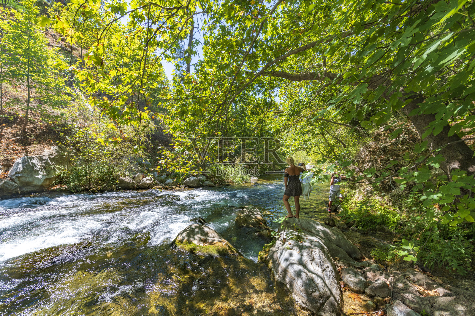 年轻女子在瀑布里玩。年轻女子在森林里游荡。照片摄影图片