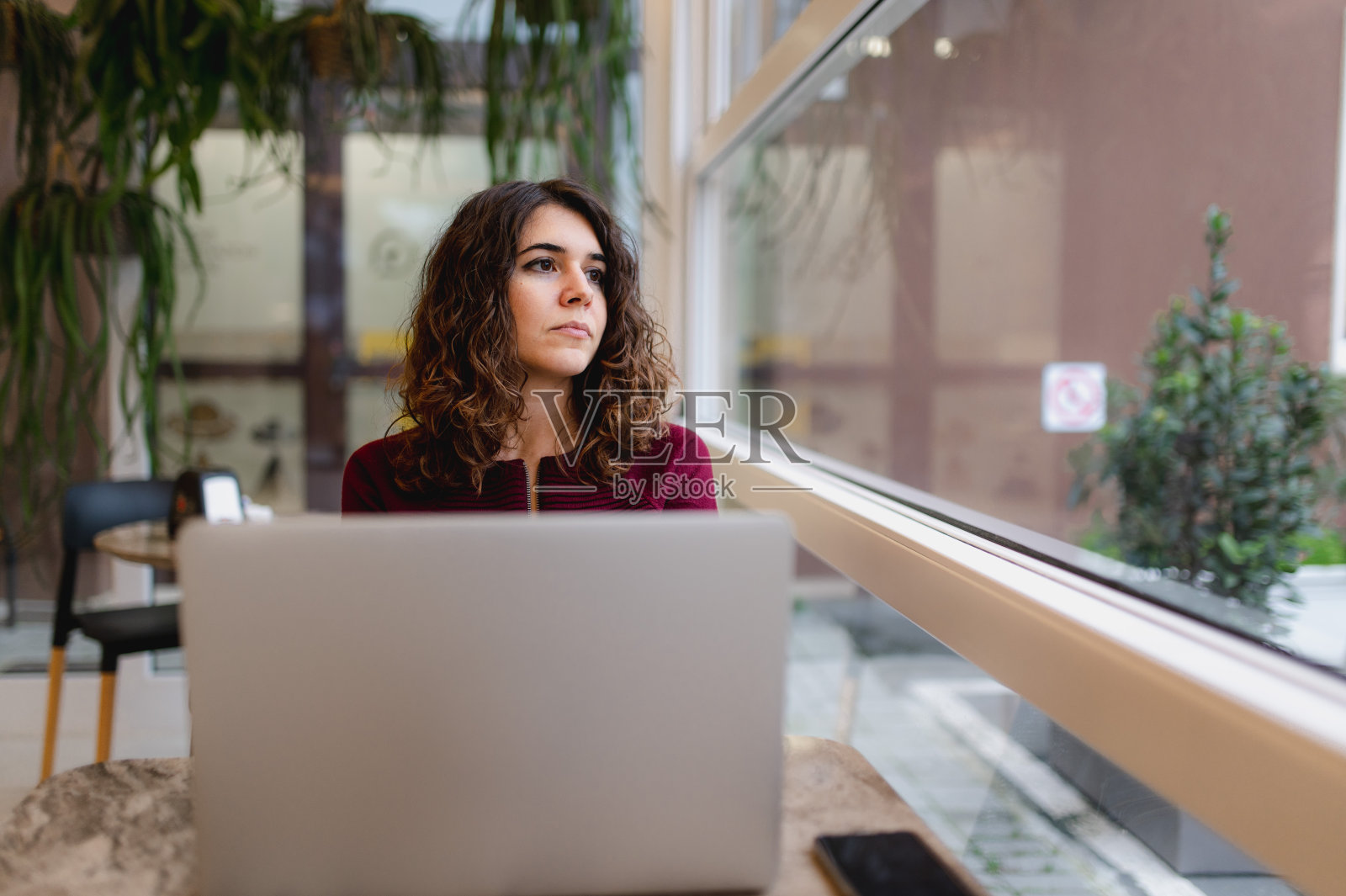 一名女性坐在咖啡馆的桌子上使用笔记本电脑。照片摄影图片