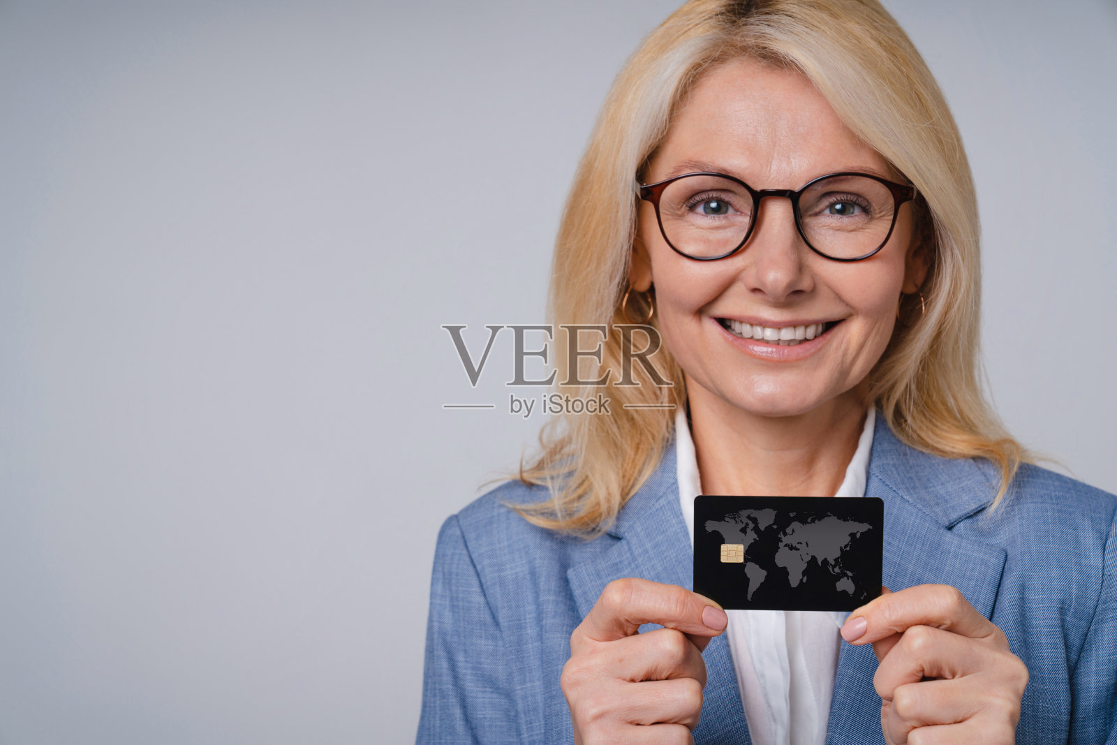 近距离肖像高级商业女性与信用卡孤立在灰色背景照片摄影图片